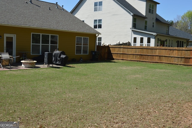 rear view of house with a patio, roof with shingles, an outdoor fire pit, a yard, and fence