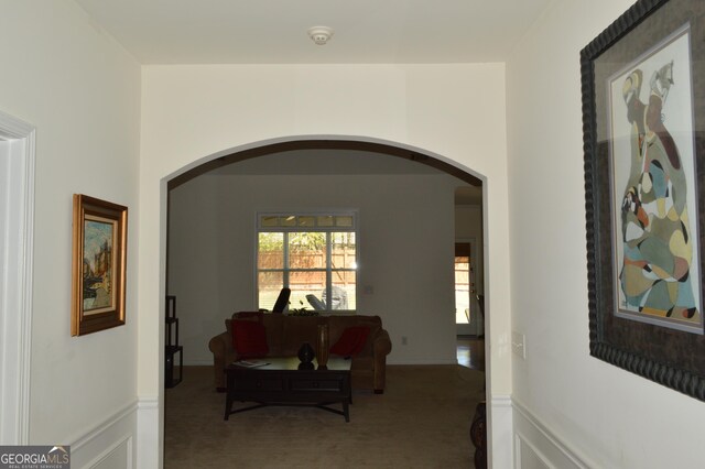 corridor with arched walkways and carpet