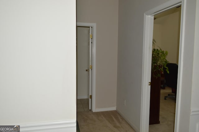 corridor featuring light colored carpet and baseboards