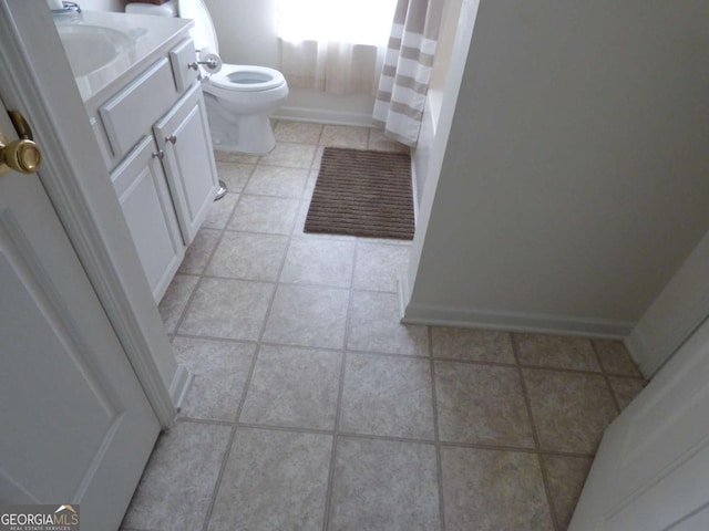 bathroom featuring tile patterned flooring, vanity, baseboards, and toilet
