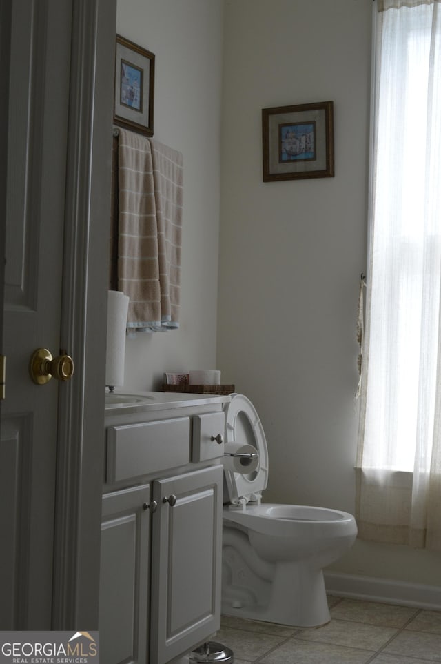 bathroom with tile patterned flooring, toilet, vanity, and a healthy amount of sunlight