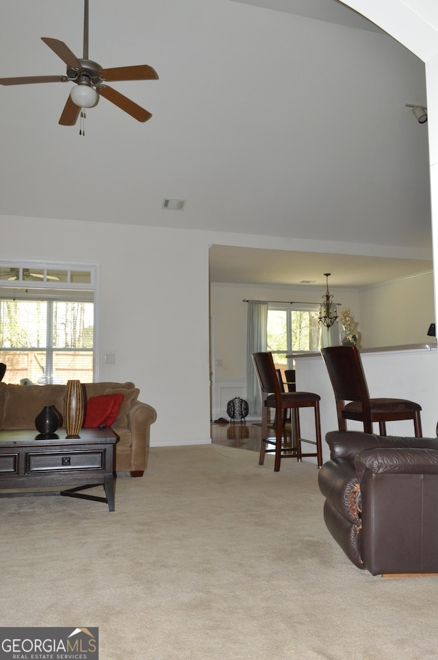 living area featuring visible vents, high vaulted ceiling, carpet flooring, and ceiling fan with notable chandelier