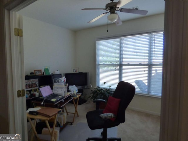 carpeted home office with ceiling fan and baseboards