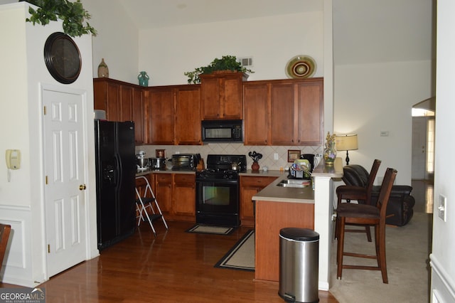 kitchen with dark wood-style floors, black appliances, visible vents, decorative backsplash, and a sink
