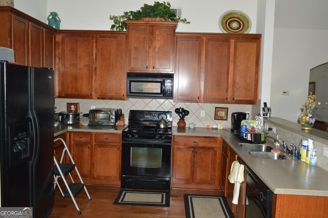 kitchen featuring a peninsula, light countertops, backsplash, black appliances, and a sink