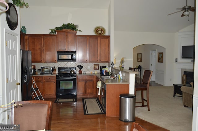 kitchen with tasteful backsplash, arched walkways, a ceiling fan, a peninsula, and black appliances