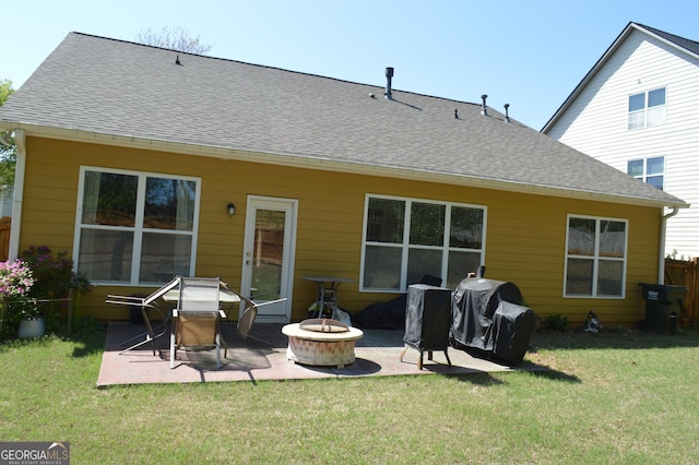 rear view of property featuring a shingled roof, a patio, a fire pit, and a lawn