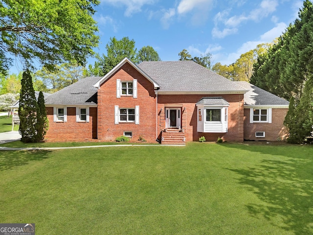 view of front of house with brick siding, a front yard, and a shingled roof