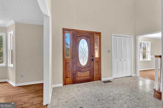 entrance foyer with baseboards, ornamental molding, and a high ceiling