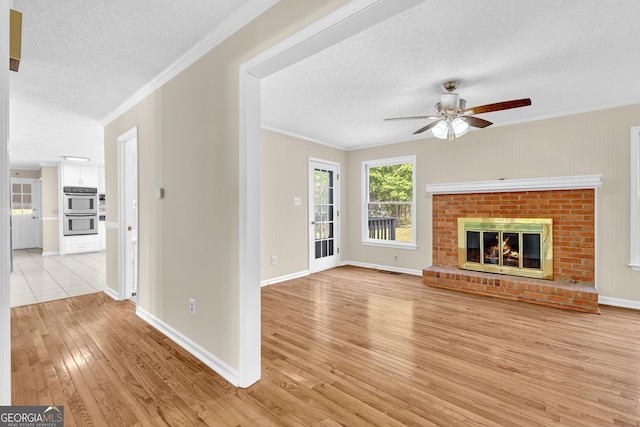 unfurnished living room with a textured ceiling, light wood-style floors, ceiling fan, ornamental molding, and baseboards