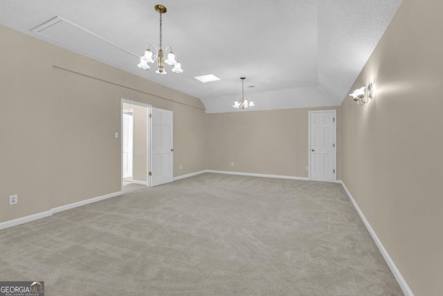 carpeted spare room featuring a chandelier, vaulted ceiling, and baseboards