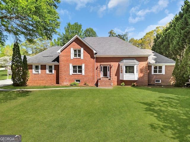 view of front of home with brick siding, a front yard, and roof with shingles