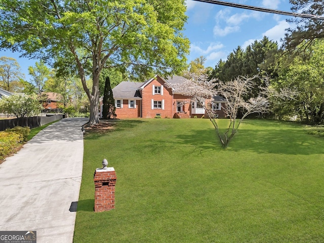 view of front of home featuring concrete driveway, a front lawn, and brick siding