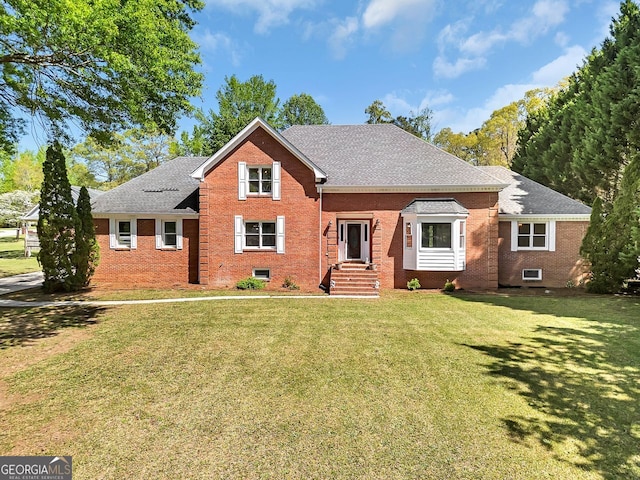 view of front of home with brick siding, a front yard, and a shingled roof