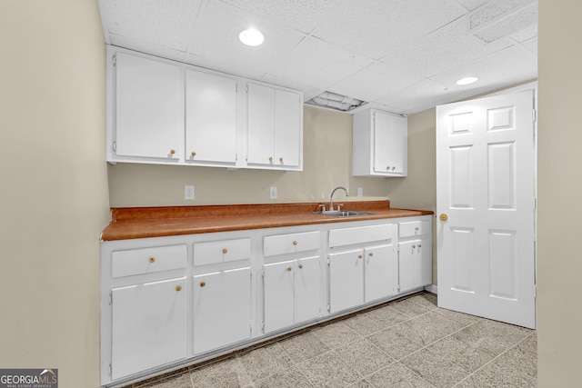 kitchen featuring a sink, white cabinets, a drop ceiling, and recessed lighting