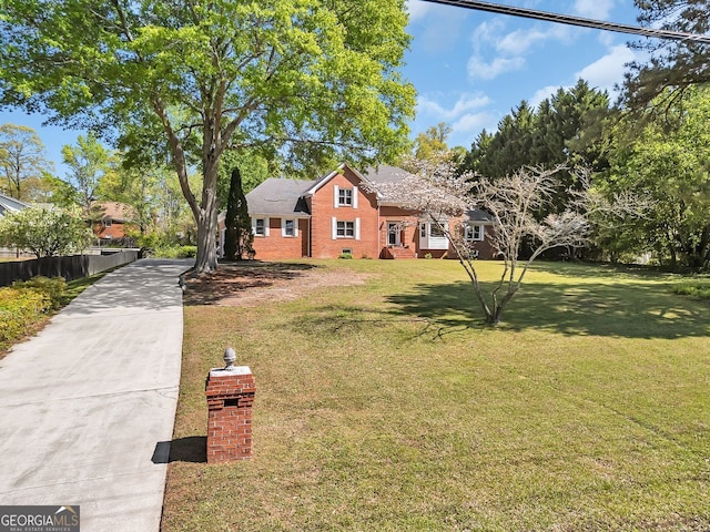 view of front facade featuring driveway, brick siding, and a front yard