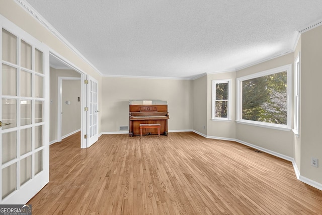unfurnished living room featuring french doors, wood finished floors, a textured ceiling, ornamental molding, and baseboards