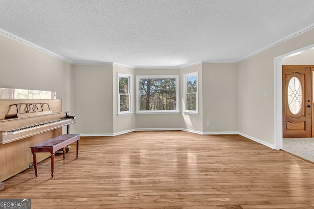 foyer entrance featuring light wood-style floors, a textured ceiling, baseboards, and crown molding