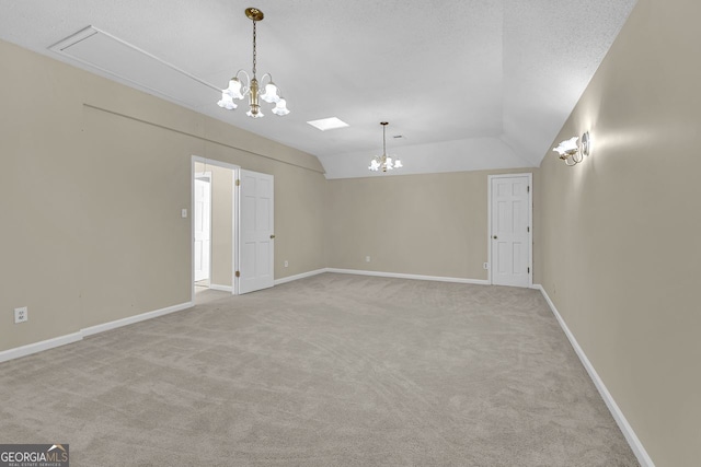 carpeted spare room featuring a chandelier, lofted ceiling, and baseboards