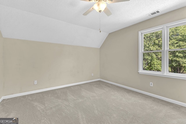 additional living space with carpet floors, baseboards, lofted ceiling, a ceiling fan, and a textured ceiling