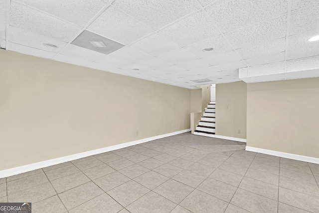 finished below grade area with a drop ceiling, stairway, and baseboards