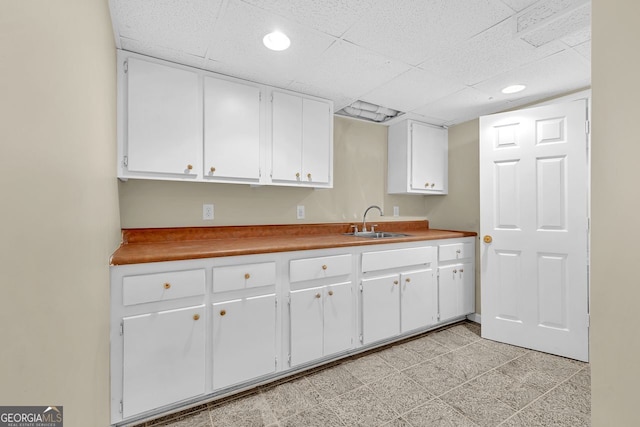 kitchen with a sink, white cabinetry, recessed lighting, and a drop ceiling