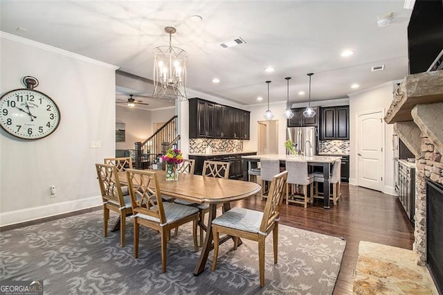 1190 Mosspointe Dr, Roswell, GA 30075 - dining area featuring stairs, crown molding, dark wood-style floors, a fireplace, and ceiling fan