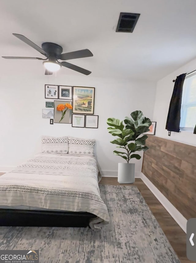 bedroom featuring baseboards, ceiling fan, visible vents, and wood finished floors