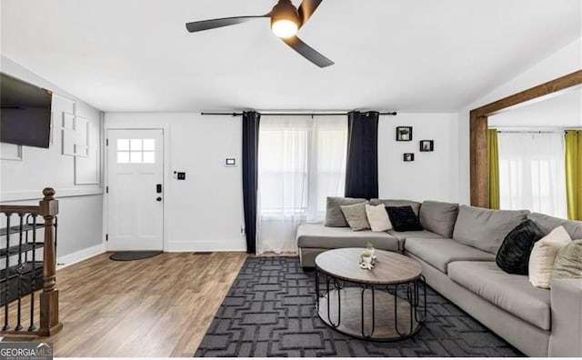 living area featuring baseboards, light wood-type flooring, and ceiling fan