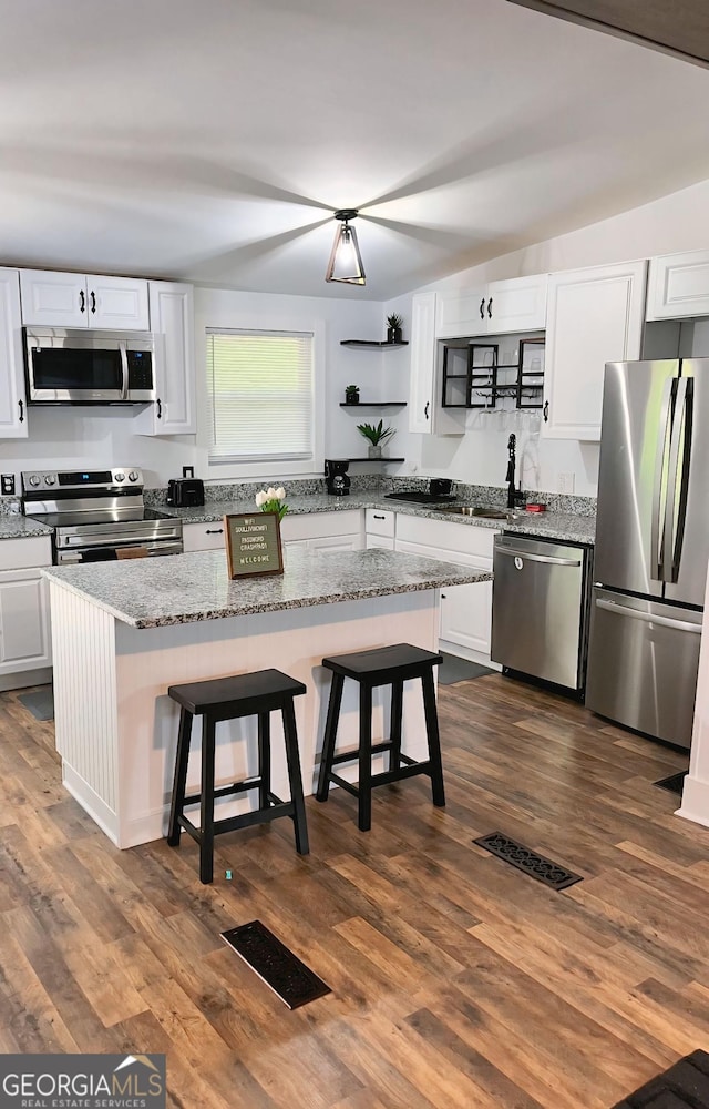 kitchen with dark wood-style floors, white cabinets, visible vents, and stainless steel appliances