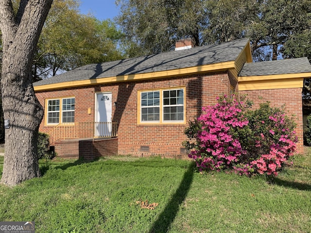 exterior space featuring brick siding, a lawn, crawl space, and a chimney