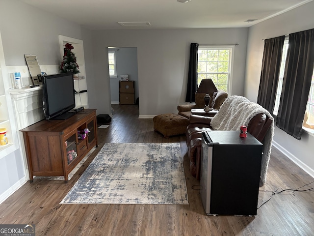 living area featuring visible vents, plenty of natural light, baseboards, and wood finished floors