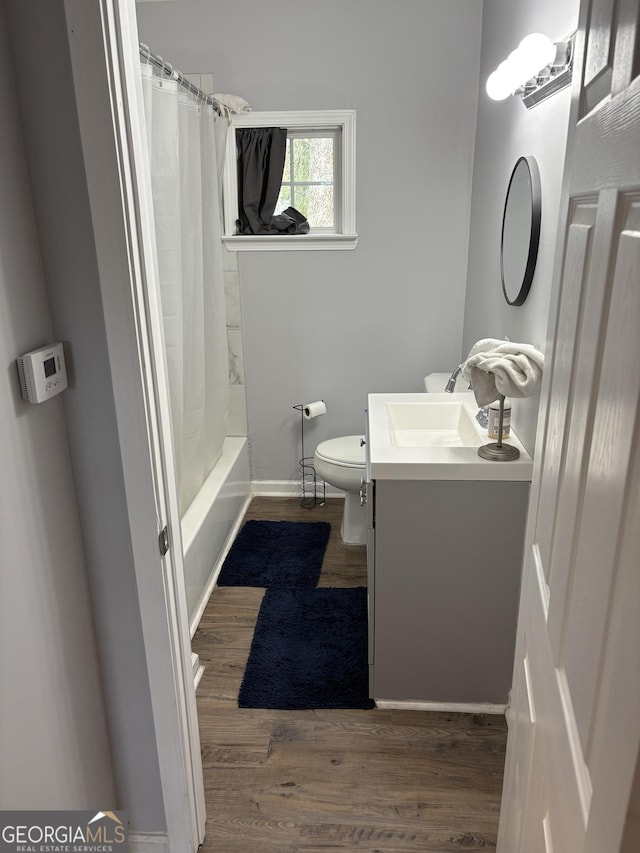 bathroom featuring baseboards, wood finished floors, vanity, and toilet