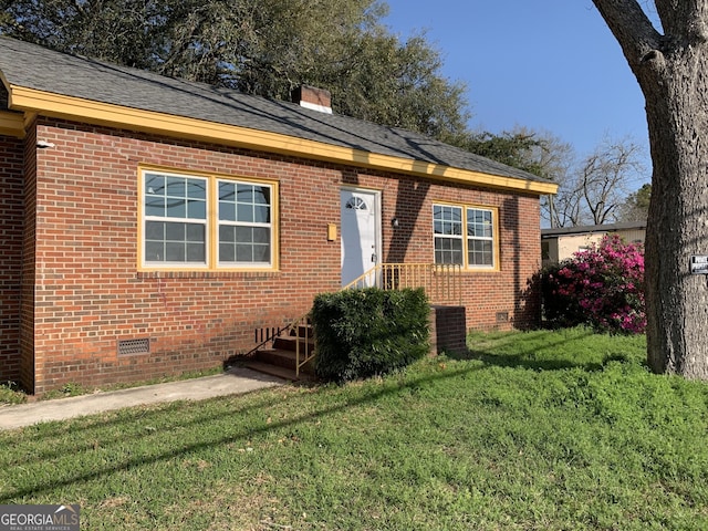 view of front facade with brick siding, entry steps, crawl space, and a front lawn