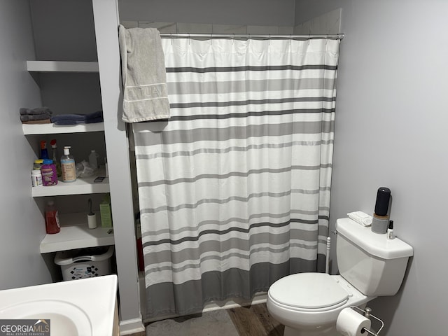 bathroom featuring toilet, a shower with curtain, and wood finished floors