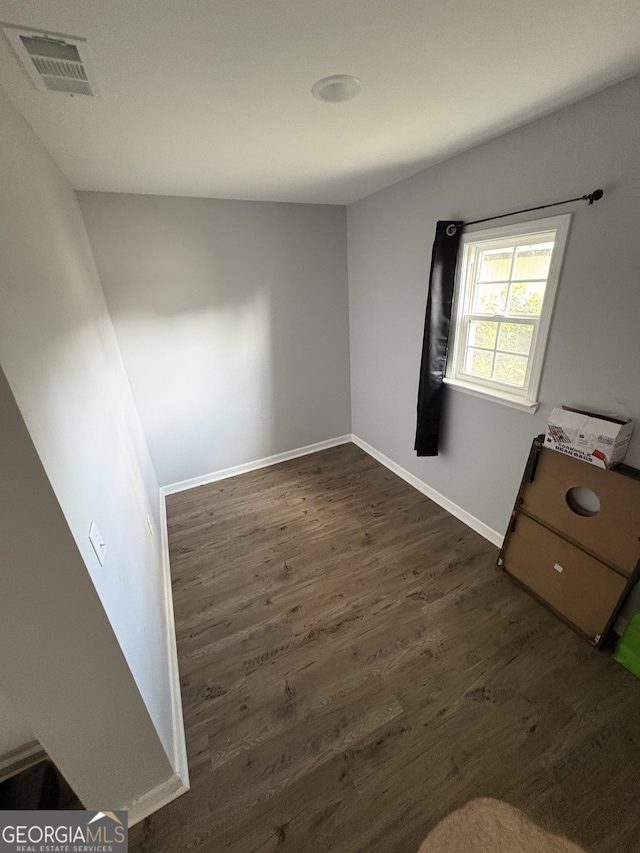 unfurnished room featuring dark wood-style floors, baseboards, and visible vents