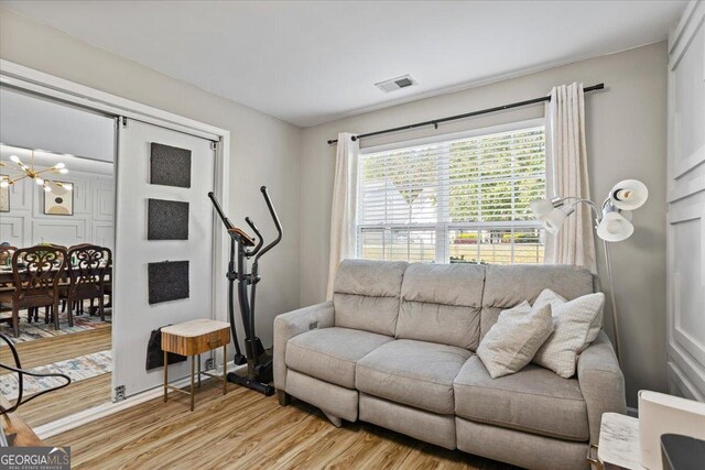 living area featuring a notable chandelier, visible vents, and light wood-style floors