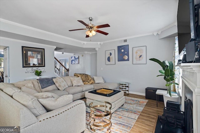 living room with visible vents, a ceiling fan, wood finished floors, stairs, and ornamental molding