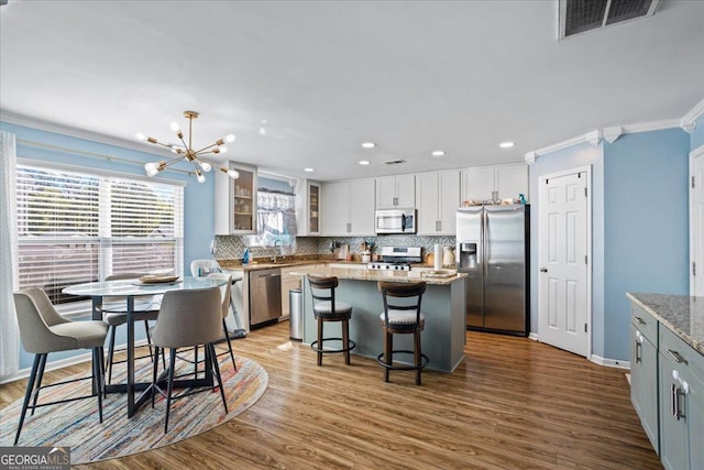 kitchen featuring stainless steel appliances, visible vents, white cabinetry, decorative backsplash, and crown molding