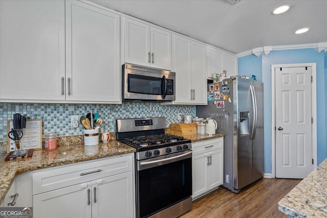 kitchen featuring white cabinets, stainless steel appliances, wood finished floors, and decorative backsplash