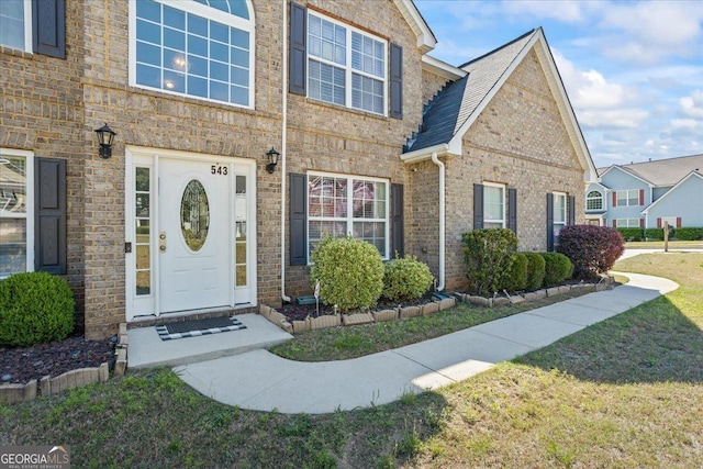 property entrance featuring brick siding and a yard