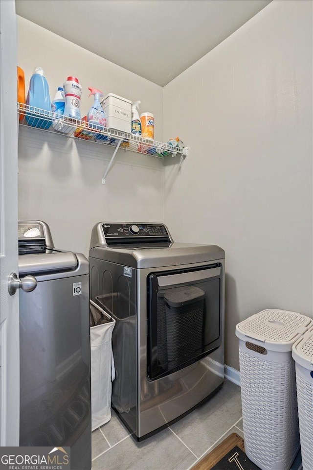 clothes washing area with washing machine and dryer, tile patterned floors, and laundry area