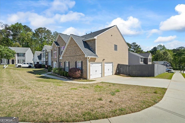 view of side of property featuring an attached garage, fence, a yard, and driveway