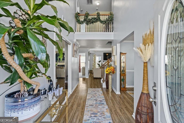 foyer featuring baseboards, wood finished floors, and a high ceiling