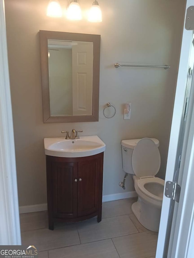bathroom featuring baseboards, toilet, tile patterned floors, and vanity