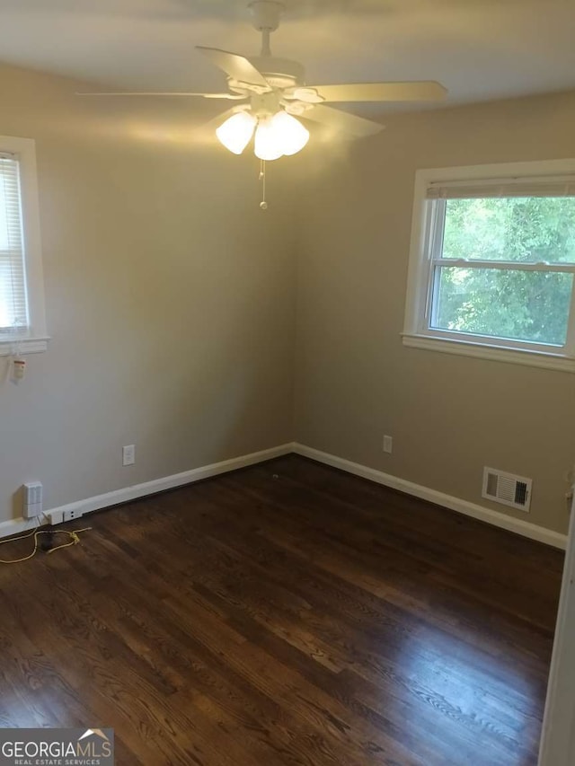 unfurnished room featuring dark wood-style flooring, baseboards, ceiling fan, and visible vents