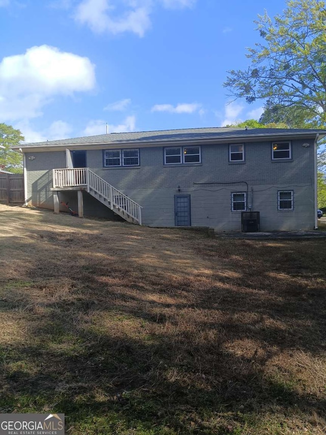 rear view of house featuring cooling unit, a yard, fence, and stairs