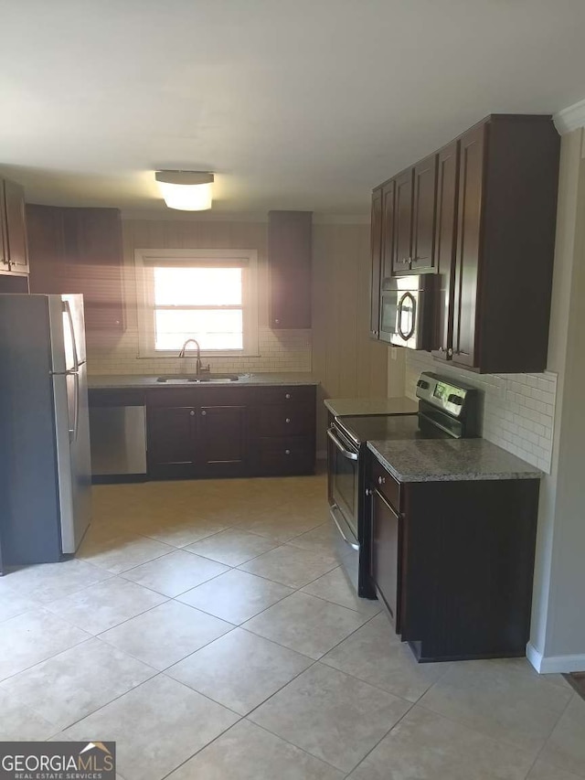 kitchen featuring a sink, tasteful backsplash, appliances with stainless steel finishes, and light tile patterned flooring