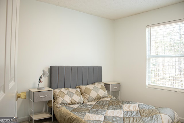 bedroom with baseboards, radiator heating unit, and a textured ceiling