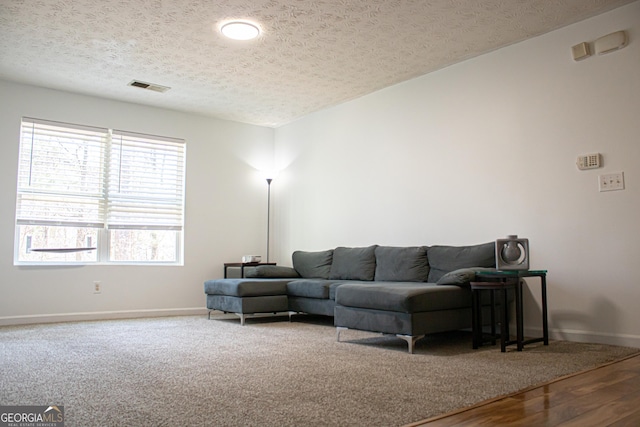living area featuring a textured ceiling, baseboards, and visible vents